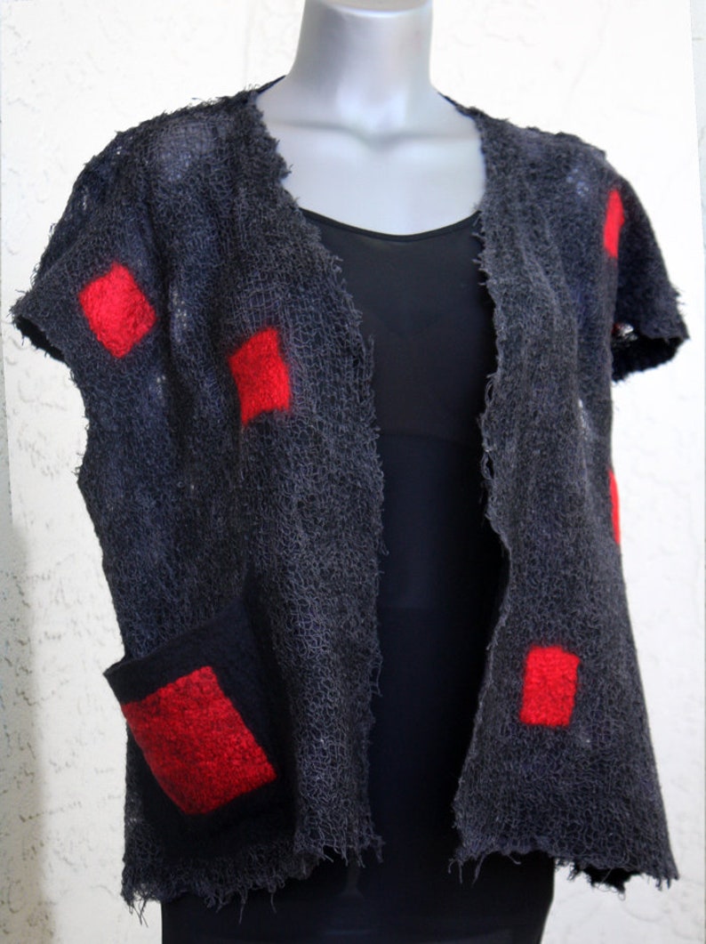 May include: A dark gray, open-front vest with short sleeves and a single pocket. The vest features several bright red square patches. The garment is displayed on a mannequin.