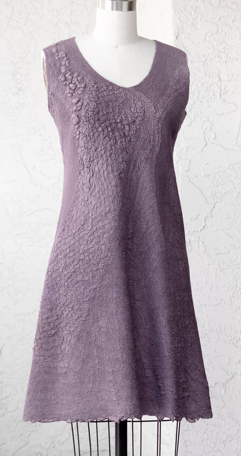 May include: A sleeveless, A-line dress in a deep purple color. The dress has a textured, crinkled fabric and a scoop neckline.