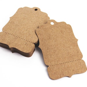 May include: A stack of brown paper gift tags with a scalloped edge and a hole for string. The tags are blank and ready to be written on.
