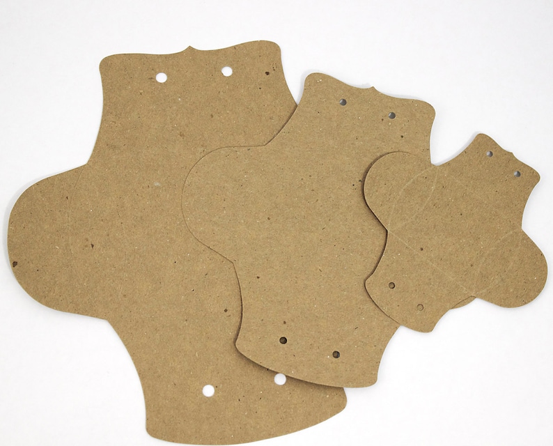 Puede incluir: Tres compresas menstruales de cart&oacute;n marr&oacute;n de diferentes tama&ntilde;os. Las compresas tienen agujeros perforados.