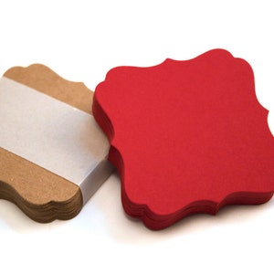 May include: Two stacks of brown and red paper gift tags with scalloped edges. The tags are blank and ready for writing.