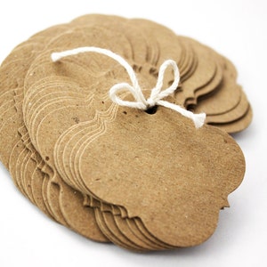 May include: A stack of brown paper gift tags with scalloped edges, tied together with a white string.