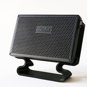 May include: A black speaker with a perforated front panel, mounted on a curved black stand. The speaker has the brand name "Teufel" on the front. The design is modern and minimalist, suitable for home audio.