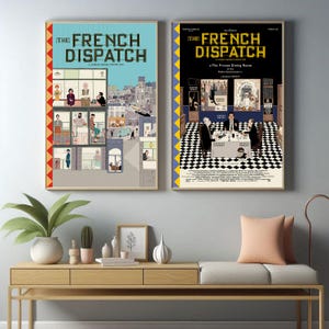 Puede incluir: Se muestran dos carteles enmarcados de la película "The French Dispatch". Los carteles presentan ilustraciones detalladas con una estética vintage. Uno tiene un fondo azul, el otro un fondo negro. Los carteles se exhiben encima de una consola de madera.