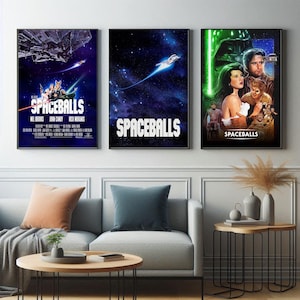 May include: Three framed movie posters for the film "Spaceballs" are displayed on a wall. The posters feature vibrant space-themed artwork with the film's title prominently displayed. The posters are framed in black and hang above a gray sofa.