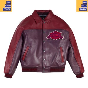 May include: A burgundy and purple leather jacket with a collared neckline and a button-up front. The jacket features a patch with text on the chest and ribbed cuffs and hem. The sleeves are burgundy, and the body is purple.