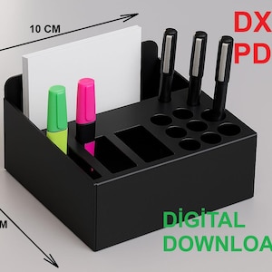 Op de afbeelding: Zwarte bureau-organizer, 10 cm x 10 cm, met vakken voor pennen, markeerstiften en notitiepapier. Bevat de tekst "DXF PDF" en "DIGITALE DOWNLOAD". Twee markeerstiften zijn groen en roze. Pennen zijn zwart.