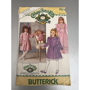 Könnte beinhalten: Ein Vintage-Schnittmuster von Butterick für Cabbage Patch Kids-Outfits. Das Muster zeigt Illustrationen von Kinderkleidern in Rosa und Lila. Enthält einen Bonus-Bügeltransfer.