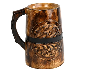 May include: A wooden mug with a dark brown finish and a carved floral design. The mug features a black band around the middle and a curved handle. The mug is made of wood and has a rustic appearance.