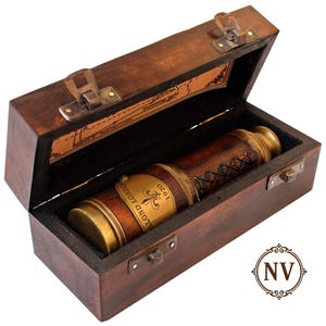 May include: A vintage brass and leather telescope in a dark wooden box. The telescope is brown with brass detailing, and the box is open, revealing a black interior. The telescope has the words "LLOYD LONDON 1920" on it. The box has a leather handle.