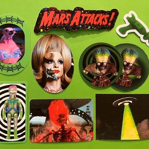 May include: A collection of stickers featuring characters and imagery from the movie "Mars Attacks!" including a chihuahua in a bra, a woman with a partially destroyed face, and alien figures. The stickers are on a green background.