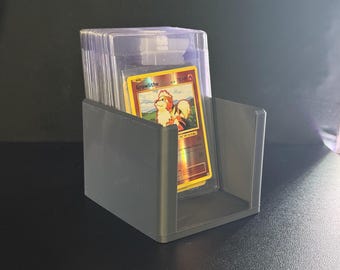 May include: A gray plastic card holder containing several trading cards. The top card features a Growlithe illustration with a red and orange color scheme. The holder is rectangular with a U-shaped opening for easy access to the cards.