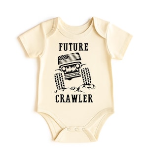 May include: Cream-colored baby bodysuit with a black graphic of a jeep and the text "FUTURE CRAWLER". The jeep has an American flag design on the hood and large tires.
