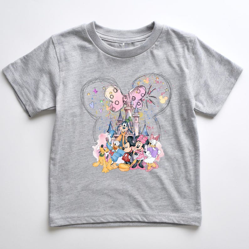 A gray t-shirt with a colorful graphic design featuring Disney characters such as Mickey Mouse, Donald Duck, Goofy, and Minnie Mouse, along with a castle and fireworks in the background.