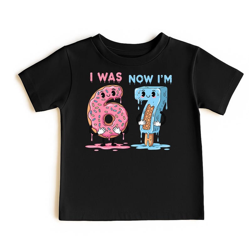 May include: Black t-shirt with the text "I WAS NOW I'M" above cartoon illustrations of a pink donut with sprinkles and the number 6, and a blue popsicle with the number 7. The donut and popsicle have arms and legs.