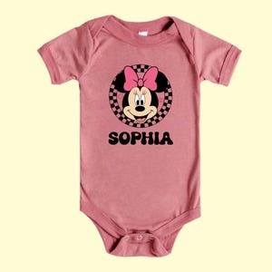 A pink baby onesie with a Minnie Mouse design and the name "Sophia" printed on it.