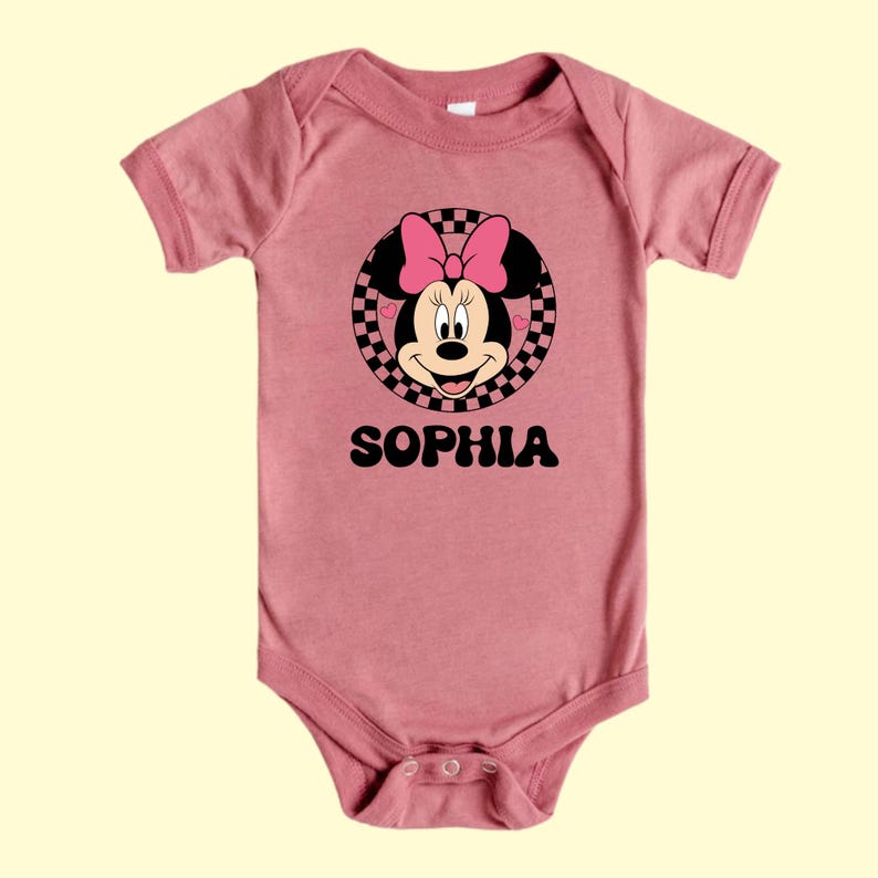 A pink baby onesie with a Minnie Mouse design and the name "Sophia" printed on it.