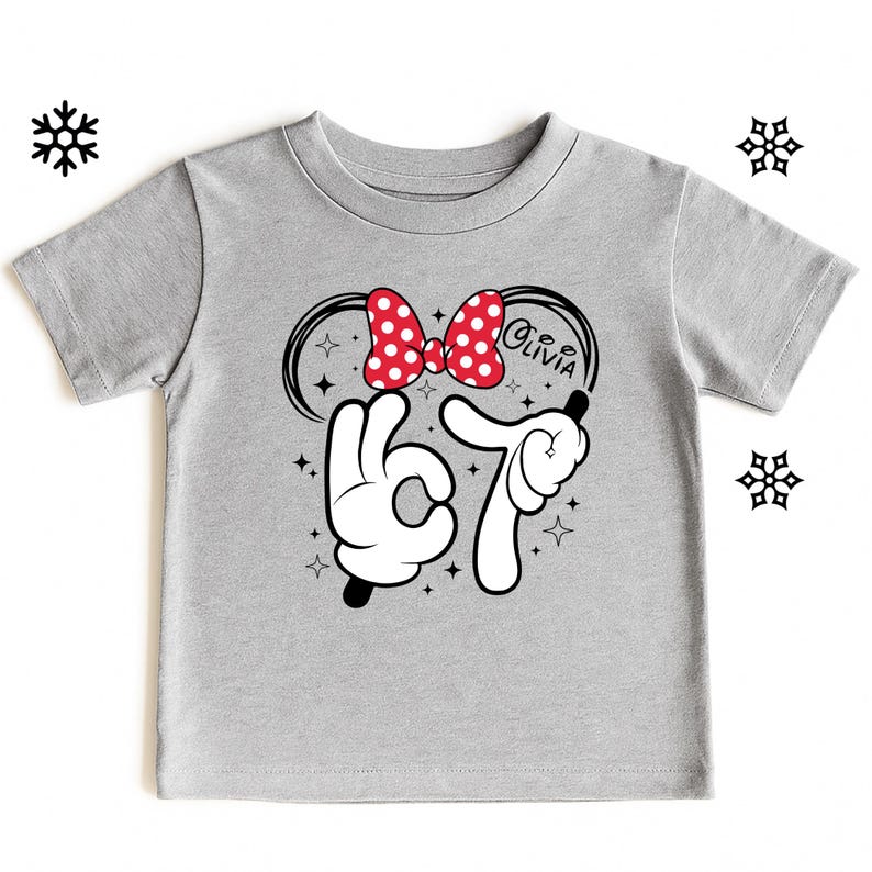 A gray t-shirt with a graphic design featuring a red bow, a peace sign, and the text "Olivia" along with a snowflake.