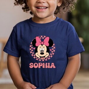 A young child wearing a blue t-shirt with a Minnie Mouse graphic and the name "Sophia" printed below it.