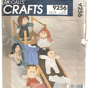 May include: McCall's Crafts 9256 sewing pattern envelope for 40.5cm soft-sculptured dolls. The cover features five fabric dolls with yarn hair and various outfits, including dresses and overalls, posed on a wooden toddler gym structure.