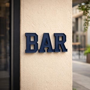 May include: Navy blue, three-dimensional letters spelling "BAR" are mounted on a textured, beige wall. The letters have a classic, blocky font, and the scene suggests a bar or establishment.