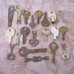 May include: A collection of vintage keys, some with rust and wear, others in better condition. The keys are made of metal and have various shapes and sizes. Some keys have markings, including "Kwikset" and "10721".