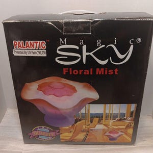 May include: A black box with the words "Magic Sky Floral Mist" in white and red. The box features an image of a decorative glass bowl with pink and orange hues. The brand name "Palantic" is also visible.