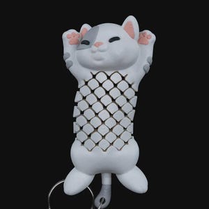 May include: A white cat-shaped keychain with a lattice design on its body. The cat has pink accents on its ears and paws, and a gray patch over one eye. The keychain includes a silver keyring and chain.