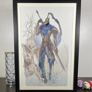 May include: Framed artwork featuring a watercolor illustration of a knight in silver armor with blue accents, holding a spear and sword. A wolf stands beside the knight. The artwork is in a black frame.