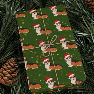 May include: Green wrapping paper featuring a repeating pattern of corgi dogs wearing Santa hats and gold stars. The wrapped package is tied with twine and set against a backdrop of pine needles and pine cones.