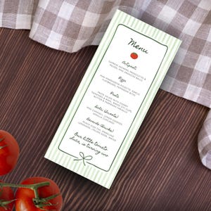 May include: A vertical rectangular menu card featuring a light green and white striped border with a dark green outline. The text includes sections for Antipasti, Pizza, Pasta, Dolci, and Bevande, with a small red tomato icon and the phrase Our little tomato Luca, is turning uno.