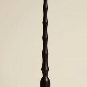 Op de afbeelding: Een hoog, donkerbruin decoratief object met een parelmoer, spiraalvormige top. De steel is een reeks verbonden, cilindrische vormen. De basis is een uitlopende, afgeronde vorm. Het object staat tegen een neutrale achtergrond.