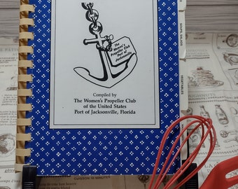 May include: A blue cookbook with a white anchor and the text "Maritime Morsels" on the cover. The book is titled "The Women's Propeller Club of the United States, Port of Jacksonville, Florida".