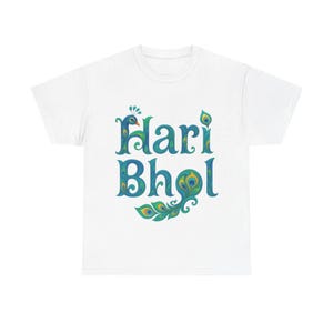 Può includere: T-shirt bianca con la scritta "Hari Bhol" in blu e verde acqua, con disegni di piume di pavone. Il testo è in un carattere decorativo, con una grafica di piuma di pavone in basso.