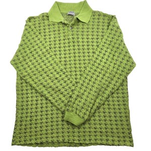 May include: A long-sleeved polo shirt in a bright green colour, with a houndstooth pattern in a darker shade of green. The shirt has a collared neckline and a buttoned placket. The cuffs and collar are a solid green colour.