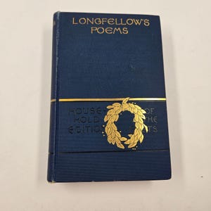 Puede incluir: Un libro de tapa dura azul marino titulado "Longfellow's Poems" con letras y detalles dorados. El libro es una "Household Edition" y presenta un diseño de corona dorada. El libro está cerrado y en buen estado.