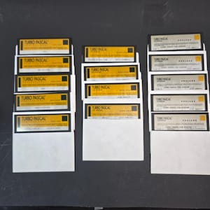 Puede incluir: Una colección de quince disquetes de 3,5 pulgadas dispuestos en tres columnas. Los disquetes cuentan con etiquetas amarillas con texto negro que dice Turbo Pascal for Windows y Borland, junto con números de disco e información de instalación.