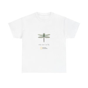 May include: White t-shirt with a dragonfly design and the words "why am i so fly", plus the National Geographic logo. The dragonfly is green and black. A casual, nature-inspired t-shirt.