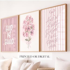 May include: A set of three framed wall art prints featuring a pink colour palette. The left print displays the text ALL GOD IS GOOD TIME. The centre print shows a bouquet of pink flowers tied with a bow. The right print features a pink striped background with the text AND IN EVERY SEASON I WILL PRAISE HIM with a bow graphic at the top.