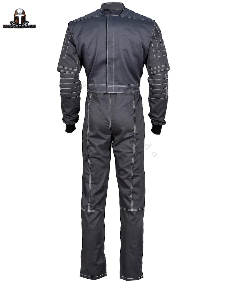 Puede incluir: Mono gris oscuro con costuras blancas. La prenda de una pieza tiene mangas largas, cuello alto y cintura entallada. Las mangas tienen detalles en capas y las perneras son rectas. Pu&ntilde;os negros visibles en las mu&ntilde;ecas.