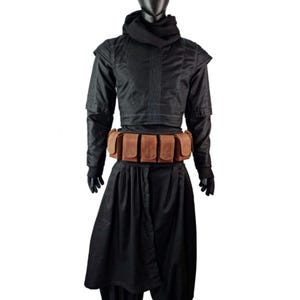 May include: A black outfit consisting of a long-sleeved top with a high collar, a matching hood, and loose-fitting trousers. A brown leather utility belt with five rectangular pouches is worn around the waist over the black fabric ensemble.