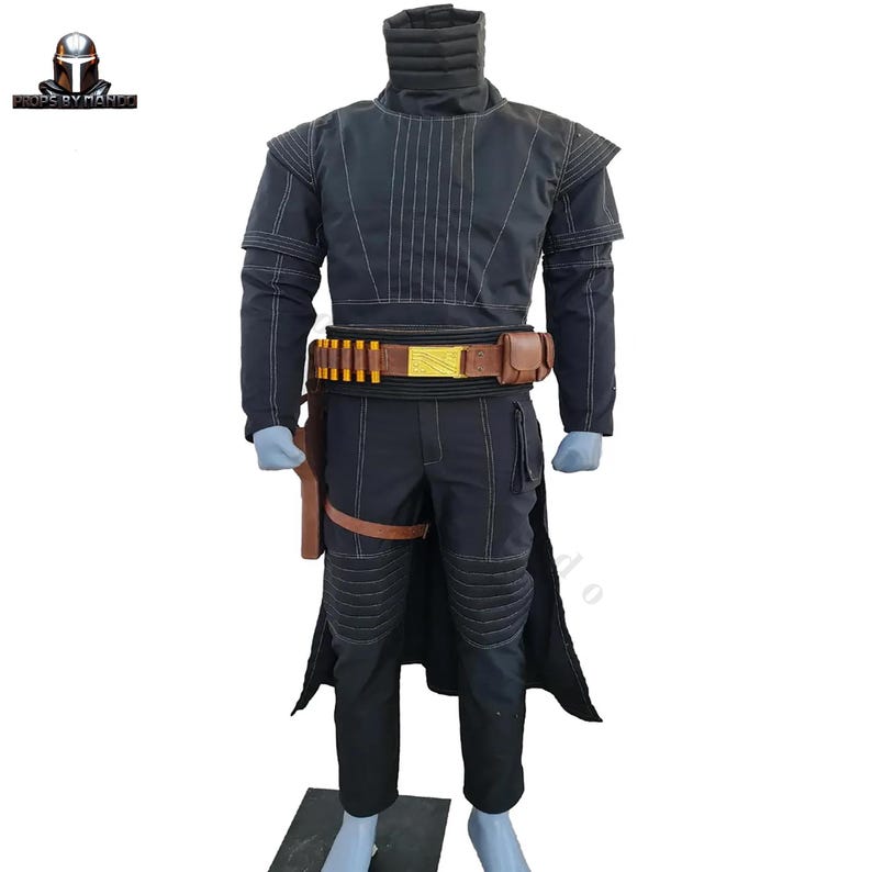 May include: A black costume with white stitching, featuring a high collar, long sleeves, and a belt with gold accents and ammunition. The costume includes matching pants, a holster, and a cape-like extension. The costume is displayed on a mannequin.