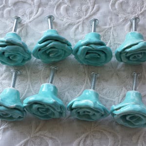 May include: Eight turquoise blue ceramic rose-shaped drawer pulls with silver metal screws.