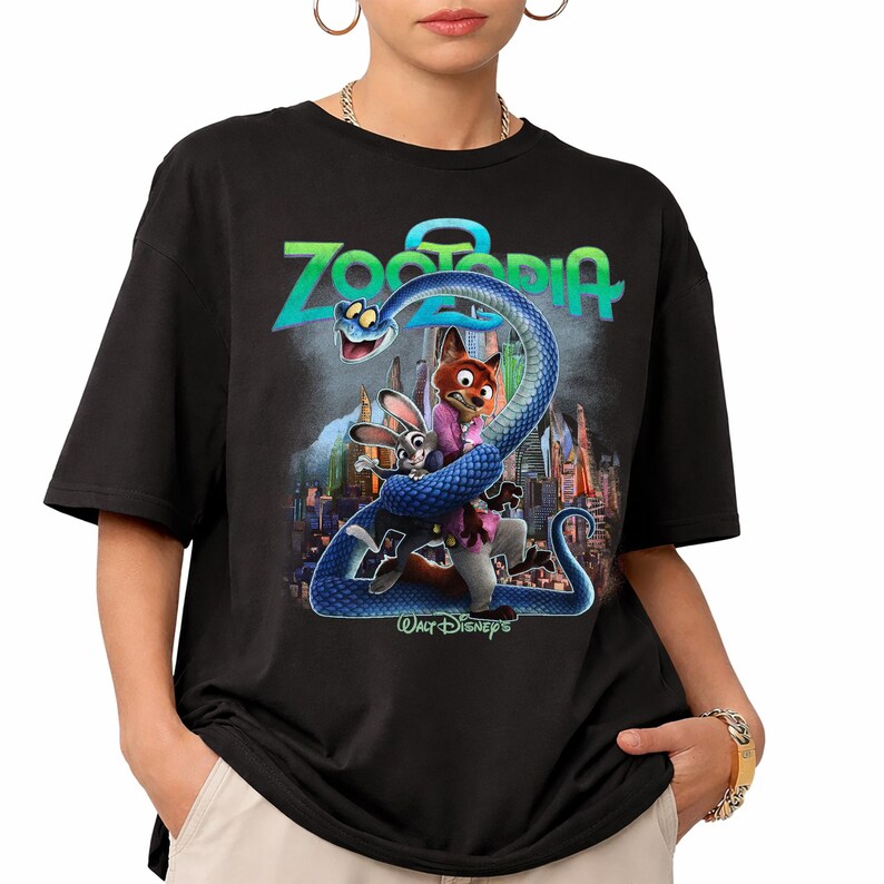 May include: Black t-shirt with a vibrant graphic from the film Zootopia. The design includes the film's title, a blue snake, and characters Judy Hopps and Nick Wilde. The Walt Disney's logo is also visible.