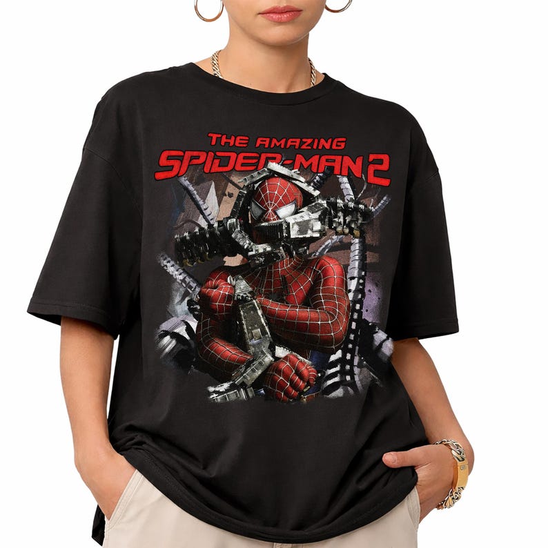 May include: Black t-shirt featuring a graphic of Spider-Man from "The Amazing Spider-Man 2." The design shows Spider-Man in his red and black suit with mechanical arms. The movie title is printed in red across the top.