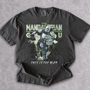 Puede incluir: Camiseta gris oscuro con un gr&aacute;fico de The Mandalorian y Grogu. El texto "THE MANDALORIAN" est&aacute; encima de la imagen, con "THIS IS THE WAY" debajo. El dise&ntilde;o est&aacute; impreso en una camiseta de manga corta y cuello redondo.