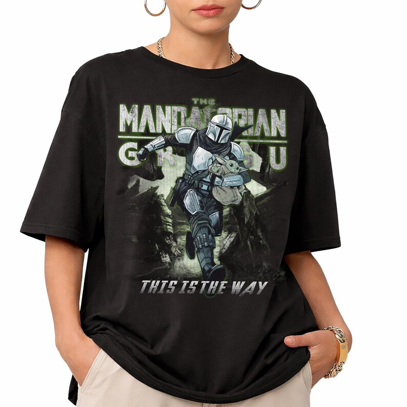 Puede incluir: Camiseta negra con un gr&aacute;fico de The Mandalorian y Grogu. El dise&ntilde;o incluye el texto "The Mandalorian" en verde y blanco, y "This is the Way" en blanco.