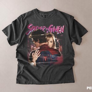 May include: Dark grey t-shirt with a graphic of Spider-Man and Gwen Stacy embracing, and the text "Spider & Gwen" in pink and blue. The shirt has a vintage, distressed appearance.