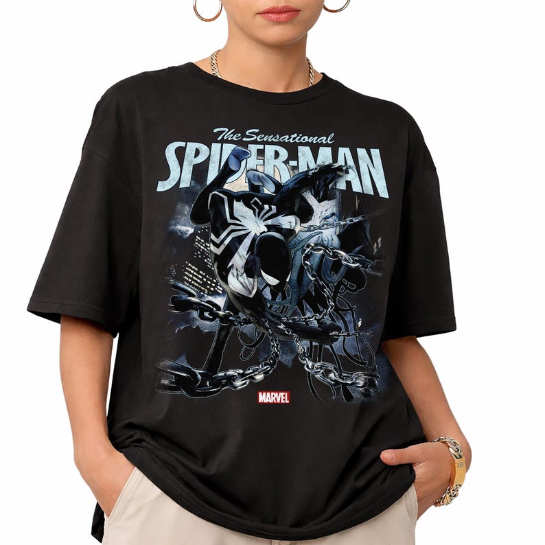 May include: Black t-shirt featuring a graphic of Spider-Man in a dynamic pose, entangled in chains. The text "The Sensational Spider-Man" is displayed above the character, with the Marvel logo at the bottom.