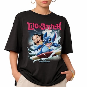 Peut inclure: T-shirt noir avec un imprim&eacute; du film Disney Lilo et Stitch. Le motif repr&eacute;sente Lilo et Stitch surfant sur une vague, avec l'inscription "Lilo & Stitch" en rose au-dessus. Le logo Walt Disney est en dessous.